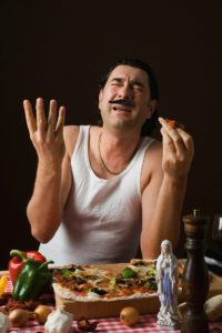 Typisch italienischer Mann isst gestikulierend eine Pizza